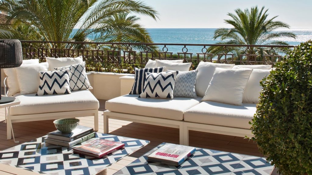 Terraza zona chill out con muebles blancos y plantas